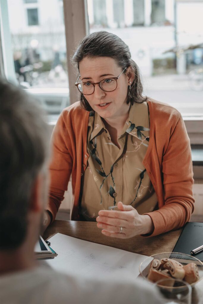 Katharina Braun am Tisch in einem Cafe mit ihren Kunden während eines systemischen Coachings